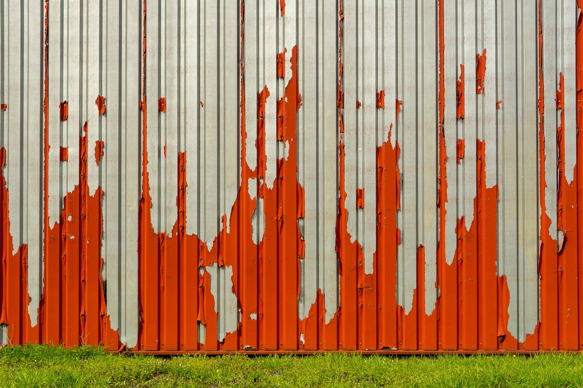 A corroded metal wall with peeling red paint, showcasing texture and decay in Temecula, CA