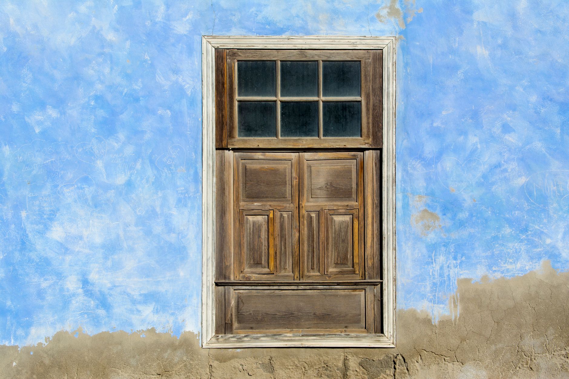 A wooden door in an old wall with peeling blue paint, showcasing rustic charm and decay in Temecula, CA