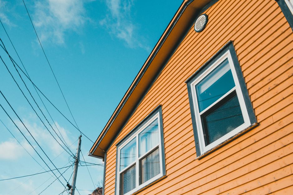 Exterior wall and trim of a painted home under a clear sky